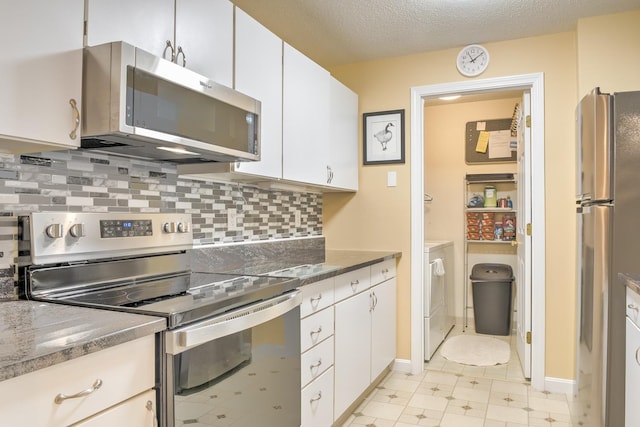 kitchen featuring a textured ceiling, backsplash, white cabinetry, stainless steel appliances, and washing machine and clothes dryer