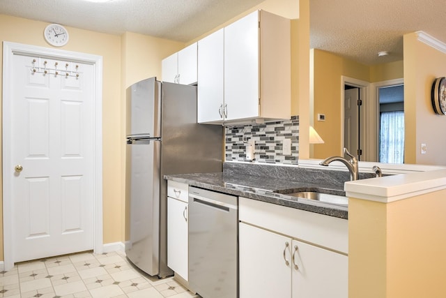 kitchen with light floors, a sink, appliances with stainless steel finishes, a textured ceiling, and white cabinetry