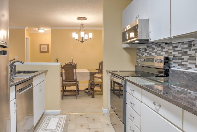 kitchen with a sink, tasteful backsplash, white cabinetry, stainless steel appliances, and crown molding