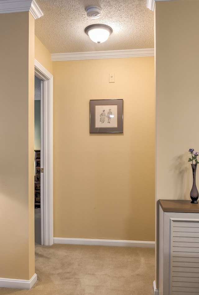 hall featuring baseboards, carpet, crown molding, and a textured ceiling