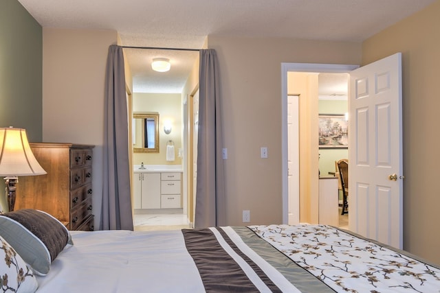 bedroom featuring a sink, a textured ceiling, and ensuite bath