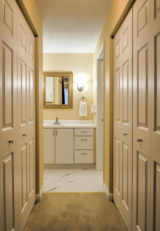 bathroom with vanity, carpet, a closet, a textured ceiling, and marble finish floor