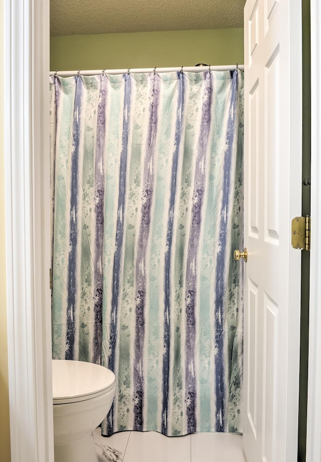 bathroom with toilet and a textured ceiling