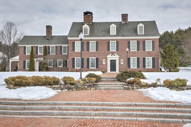 colonial inspired home featuring brick siding and a chimney