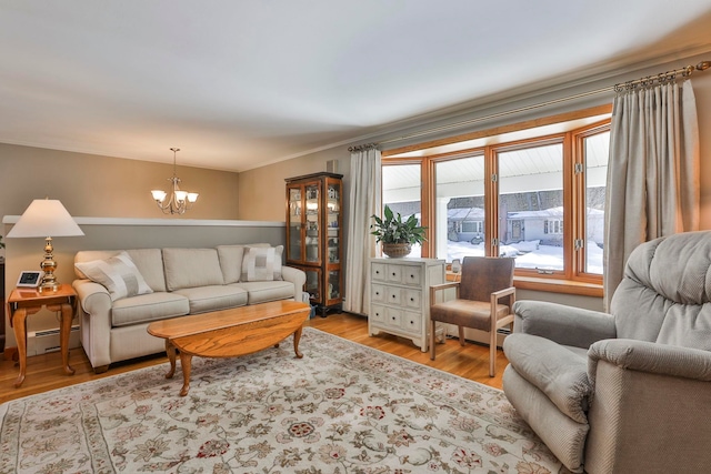 living area featuring a chandelier, baseboard heating, light wood-type flooring, and ornamental molding