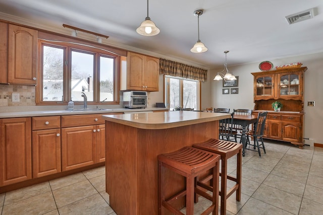 kitchen with light countertops, tasteful backsplash, visible vents, and a center island