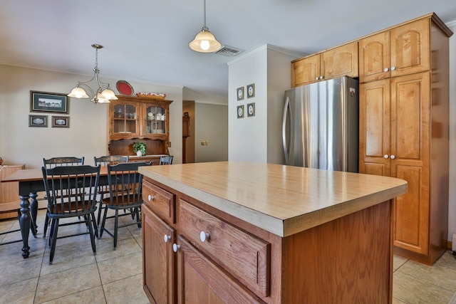 kitchen with pendant lighting, light tile patterned flooring, crown molding, and freestanding refrigerator