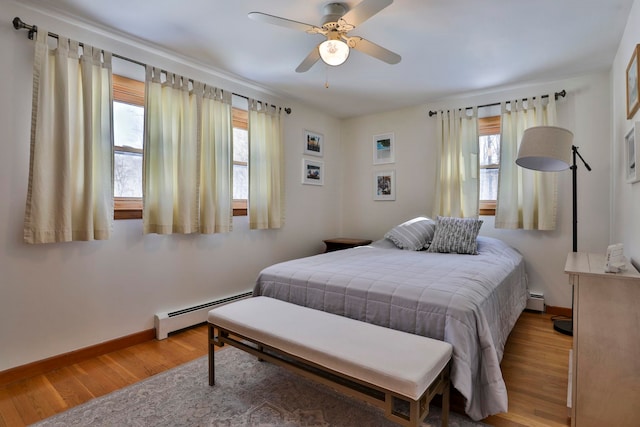 bedroom featuring ceiling fan, a baseboard radiator, baseboards, and wood finished floors