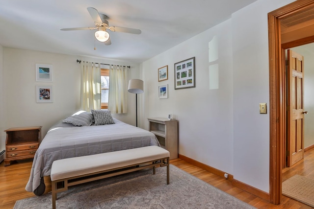 bedroom with visible vents, baseboards, wood finished floors, and a ceiling fan