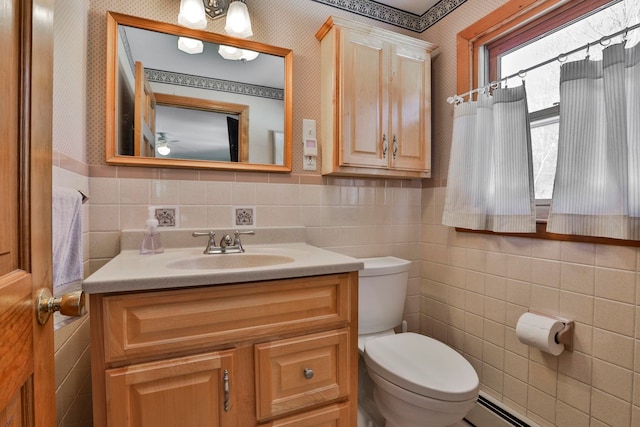 half bath with wallpapered walls, toilet, vanity, tile walls, and a baseboard radiator