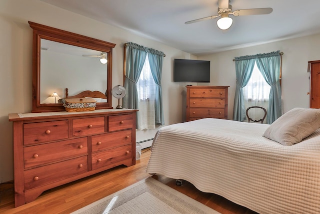 bedroom with ceiling fan, a baseboard heating unit, and light wood-style flooring