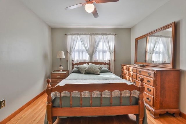 bedroom featuring baseboards, wood finished floors, and a ceiling fan