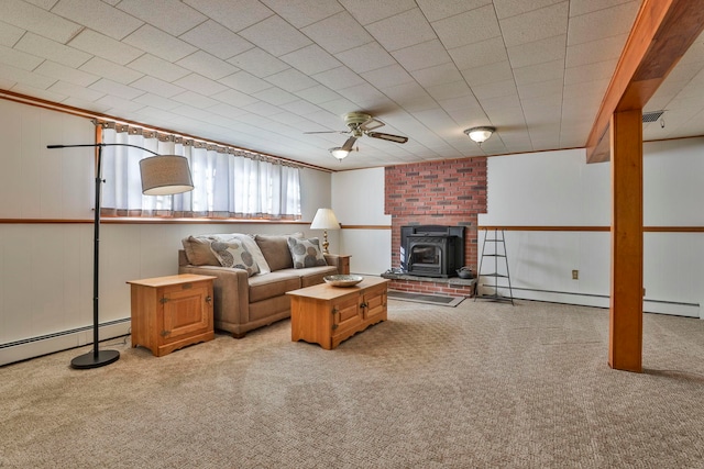 living room with visible vents, a baseboard radiator, a wood stove, ceiling fan, and light colored carpet