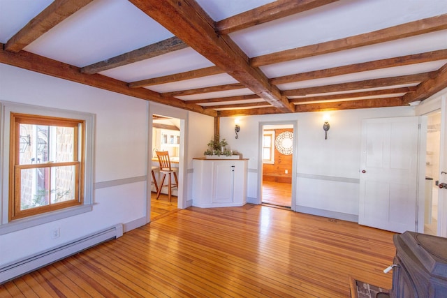 unfurnished living room with beamed ceiling, a healthy amount of sunlight, light wood-type flooring, and a baseboard radiator