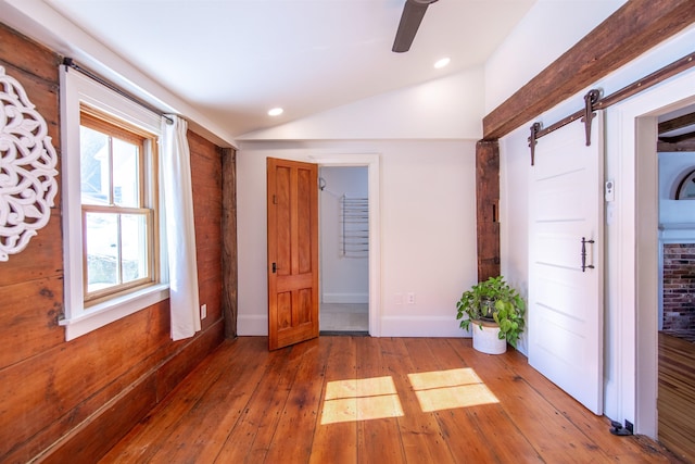 unfurnished bedroom with hardwood / wood-style floors, a barn door, recessed lighting, and lofted ceiling