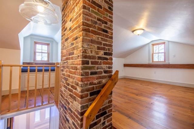 additional living space with baseboards, hardwood / wood-style flooring, and vaulted ceiling