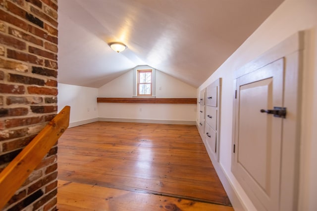 bonus room featuring light wood-type flooring, baseboards, and vaulted ceiling