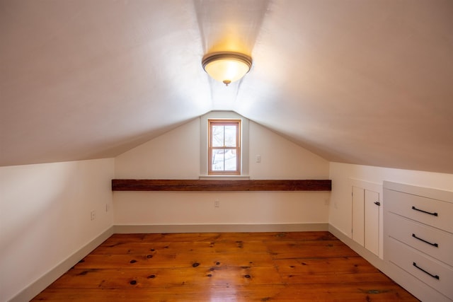 additional living space with baseboards, light wood-style floors, and vaulted ceiling