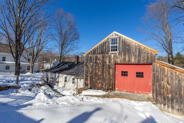 snow covered structure featuring an outbuilding and a barn