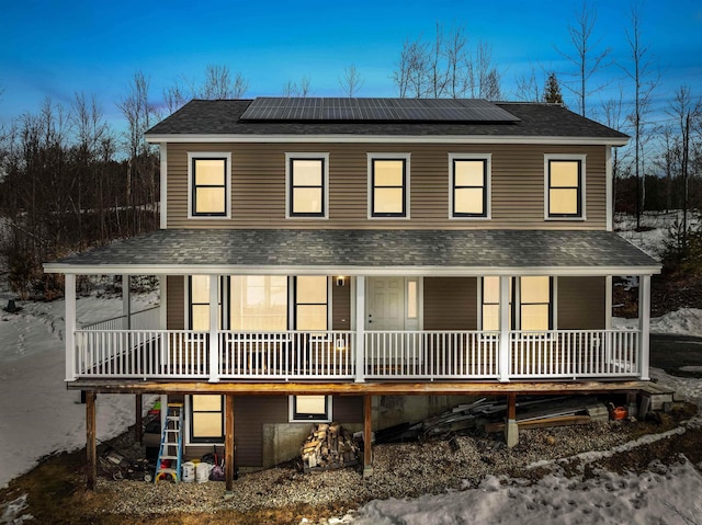 country-style home with roof mounted solar panels, a porch, and a shingled roof