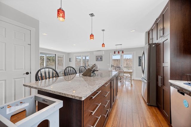 kitchen with decorative light fixtures, dishwasher, a wall mounted air conditioner, light wood-style flooring, and freestanding refrigerator