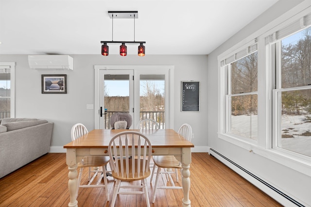 dining room featuring baseboard heating, light wood-type flooring, a wall mounted AC, and baseboards