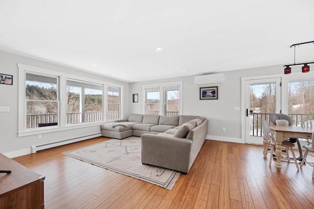 living area with a wall mounted air conditioner, wood-type flooring, baseboards, and a baseboard radiator