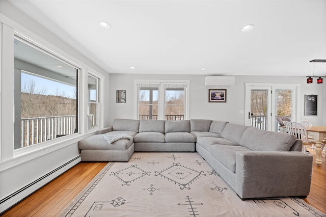 living area featuring baseboard heating, recessed lighting, a wall mounted air conditioner, and light wood-type flooring