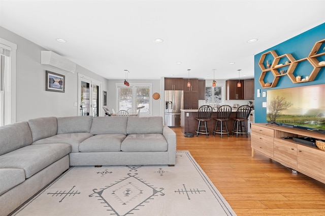 living area featuring an AC wall unit, recessed lighting, and light wood finished floors