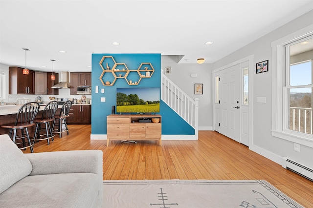 living room with light wood-type flooring, recessed lighting, stairway, a baseboard radiator, and baseboards