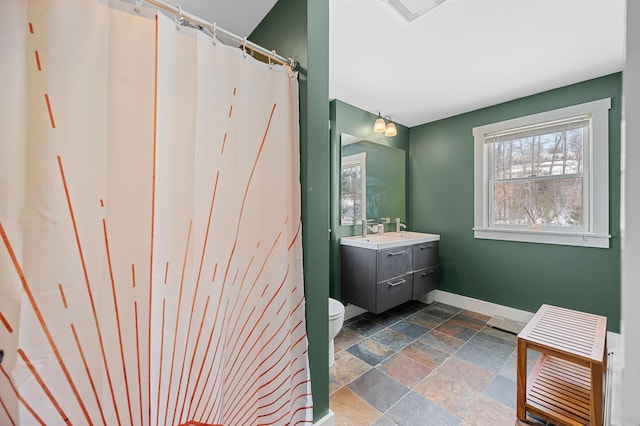 bathroom with visible vents, toilet, stone tile floors, baseboards, and vanity