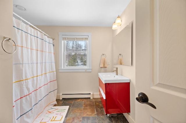 bathroom featuring stone tile floors, baseboard heating, vanity, and baseboards