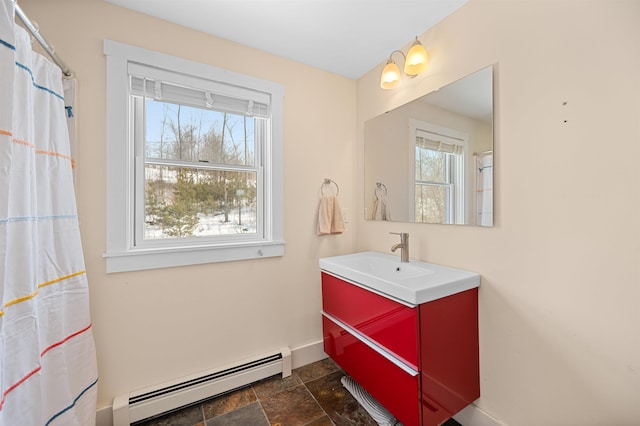 bathroom with baseboard heating, a healthy amount of sunlight, vanity, and stone tile floors