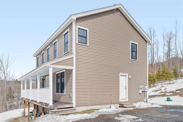 snow covered property with covered porch and entry steps