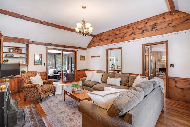 living room with a wainscoted wall, dark wood-style flooring, wooden walls, a chandelier, and vaulted ceiling with beams