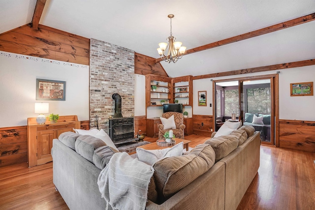 living room with wooden walls, wood finished floors, a wainscoted wall, lofted ceiling with beams, and a wood stove