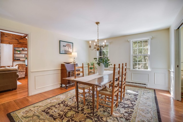 dining room with an inviting chandelier, wood finished floors, a wainscoted wall, and baseboard heating