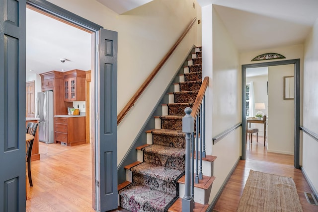 stairway with visible vents, baseboards, and wood finished floors