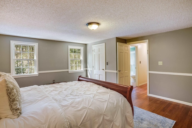 bedroom featuring baseboards, a textured ceiling, and wood finished floors