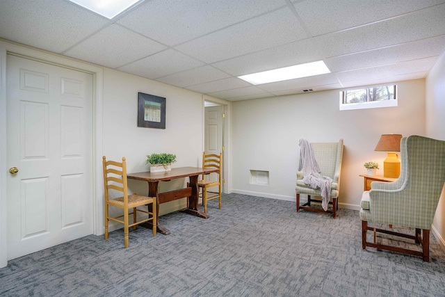 living area featuring carpet flooring, a paneled ceiling, and baseboards