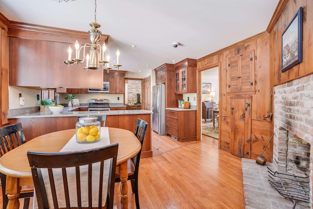 kitchen featuring light wood finished floors, a sink, appliances with stainless steel finishes, light countertops, and glass insert cabinets