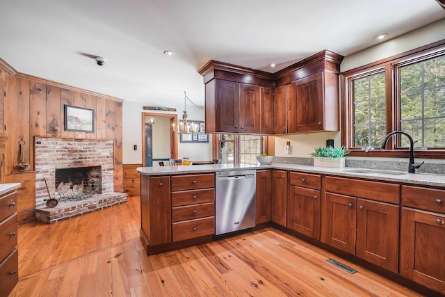 kitchen featuring light wood finished floors, a peninsula, a fireplace, a sink, and dishwasher