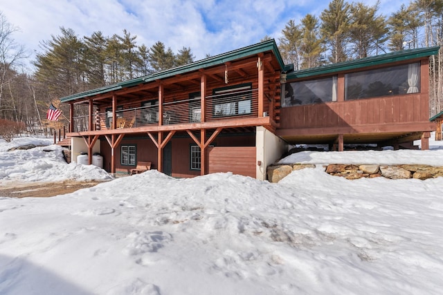 snow covered property with log exterior and a garage