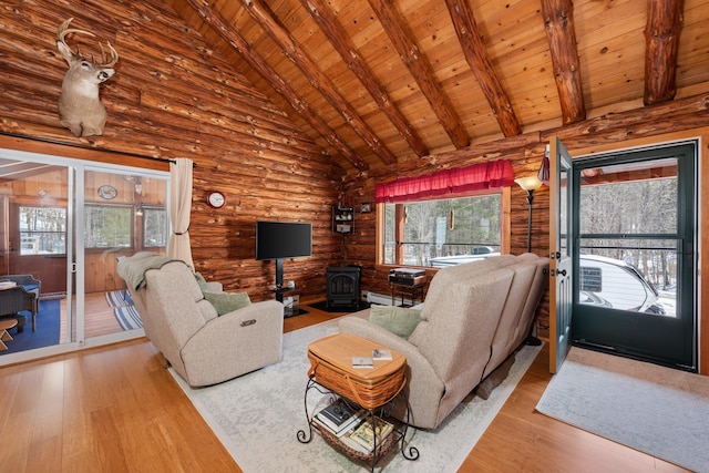 living area featuring hardwood / wood-style floors, high vaulted ceiling, beam ceiling, a wood stove, and wooden ceiling