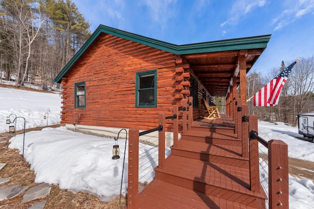 snow covered property featuring log siding