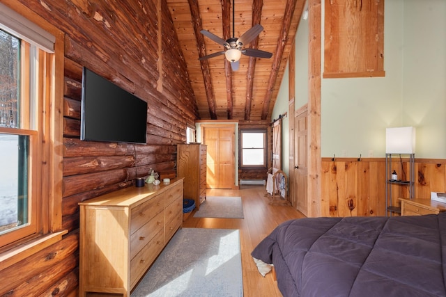 bedroom featuring log walls, lofted ceiling, wood-type flooring, wainscoting, and wooden ceiling