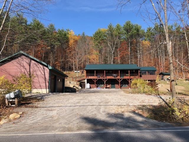 view of front of house with driveway, a wooden deck, and a forest view