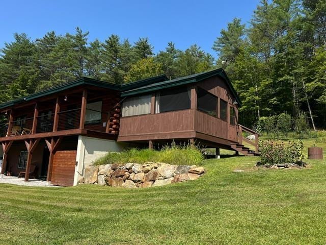 rear view of house with log siding, a yard, and a sunroom