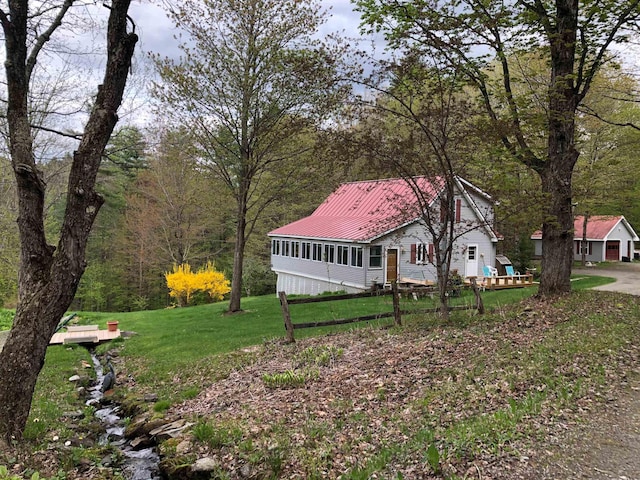 view of yard with a view of trees, fence, and a sunroom