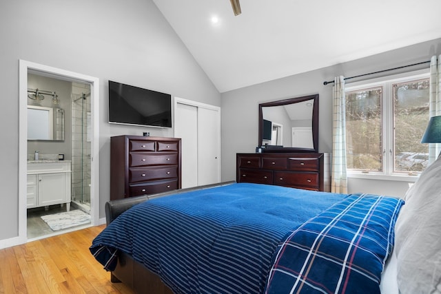 bedroom with wood finished floors, baseboards, a sink, a closet, and connected bathroom